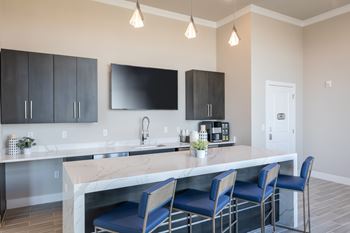 A kitchen with a marble island and blue chairs.